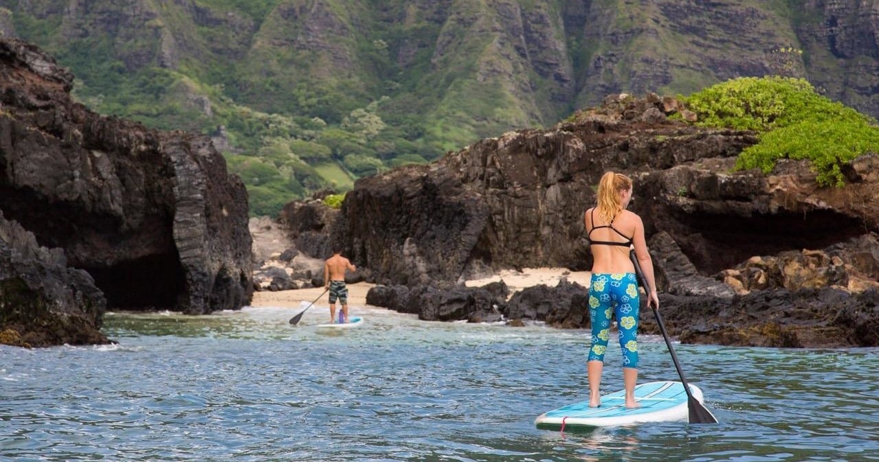 Oahu adventure tour - people on stand-up paddle boards heading toward a cove