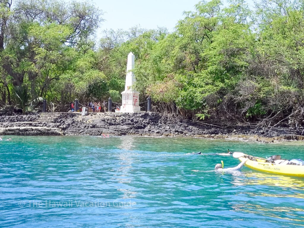 Captain Cook Monument with snorkelers and graffiti on the monument